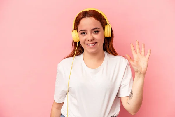 Joven Mujer Caucásica Escuchando Música Aislada Sobre Fondo Rosa Sonriente —  Fotos de Stock