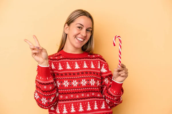 Sarı Arka Planda Izole Edilmiş Bir Noel Sopası Tutan Genç — Stok fotoğraf