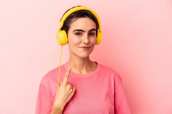 Young Caucasian Woman Listening Music Isolated Pink Background Pointing Finger — Stock Photo, Image