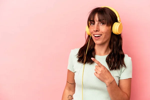 Young Argentinian Woman Listening Music Isolated Pink Background Smiling Pointing — Stock Photo, Image