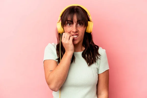 Νεαρή Αργεντίνικη Γυναίκα Που Ακούει Μουσική Απομονωμένη Ροζ Φόντο Δαγκώνοντας — Φωτογραφία Αρχείου