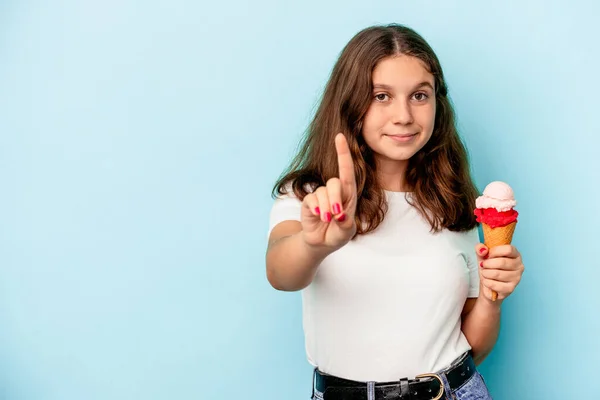 一个白人小女孩正在吃一种蓝色背景的冰淇淋 她的手指是第一位的 — 图库照片