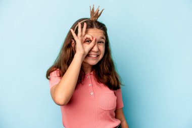 Mavi arka planda izole edilmiş prenses tacı takan beyaz bir kız heyecanlı..