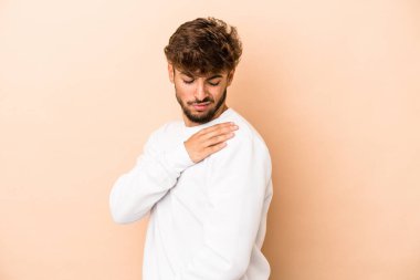 Young arab man isolated on beige background having a shoulder pain.