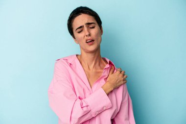 Mavi arka planda izole edilmiş, omuz ağrısı olan beyaz bir kadın..