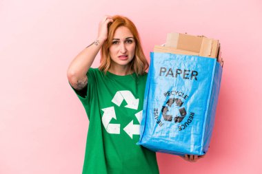 Young caucasian woman recycled paper isolated on pink background being shocked, she has remembered important meeting.