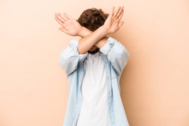 Genç Arap adam bej arka planda izole edilmiş iki kolu çapraz tutuyor, inkar kavramı.