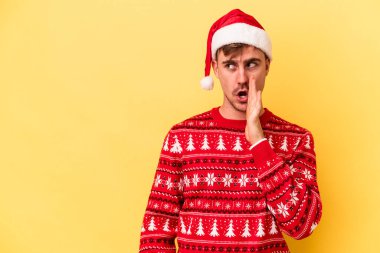 Sarı arka planda izole edilmiş bir şekilde Noel 'i kutlayan genç beyaz adam gizli bir sıcak fren haberi veriyor ve yan bakıyor.