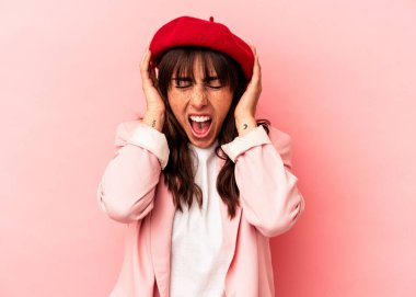 Arjantinli genç bir kadın pembe arka planda izole edilmiş kulaklarını elleriyle kapatarak yüksek sesle ses duymamaya çalışıyor..