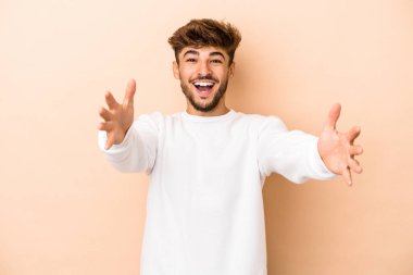 Genç Arap adam bej arka planda izole edilmiş kameraya sarıldığı için kendinden emin..