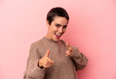 Mavi arka planda izole edilmiş genç beyaz kadın parmaklarıyla ön tarafı işaret ediyor..