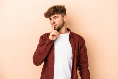 Genç Arap adam bej arka planda izole edilmiş bir şekilde bir sır saklıyor ya da sessizlik istiyor.