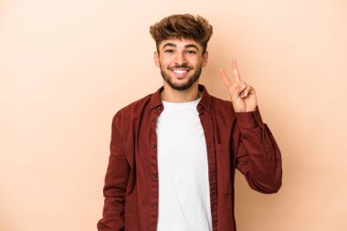 Young arab man isolated on beige background showing number two with fingers.
