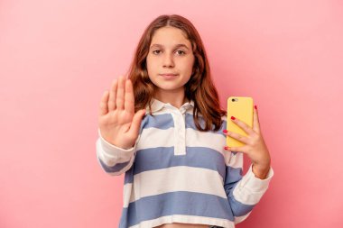 Pembe arka planda cep telefonu tutan küçük beyaz kız elini uzatıp dur işaretini göstererek seni engelliyor..