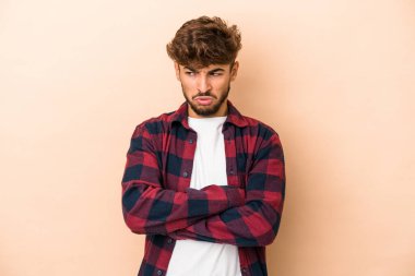 Genç Arap adam bej arka planda izole edilmiş. Tekrarlanan bir görevden yorulmuş..