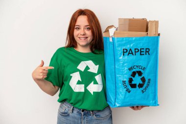 Young caucasian woman recycled paper isolated on white background person pointing by hand to a shirt copy space, proud and confident
