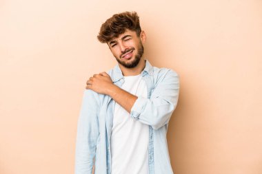 Young arab man isolated on beige background having a shoulder pain.