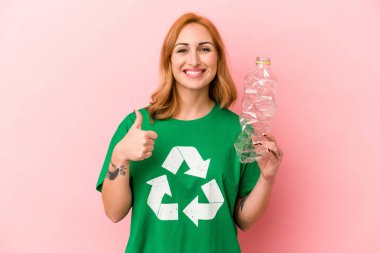 Young caucasian woman recycled plastic isolated on pink background