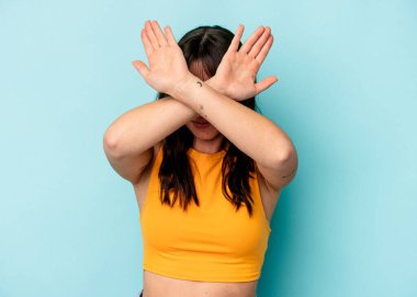 Genç Arjantinli kadın mavi arka planda izole edilmiş iki kolu çapraz tutuyor, inkar kavramı.