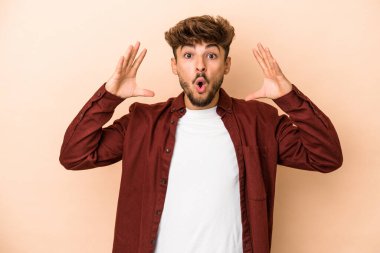 Young arab man isolated on beige background celebrating a victory or success, he is surprised and shocked.