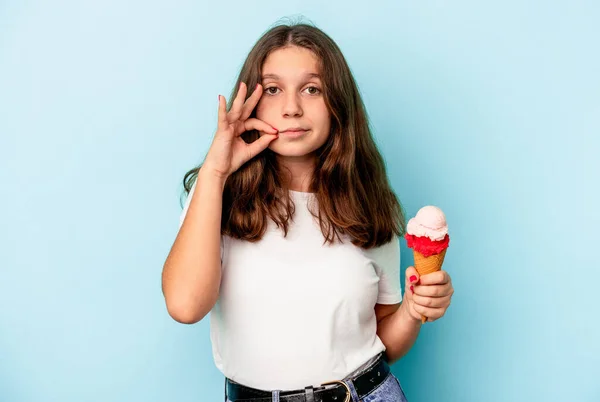 小高加索女孩吃着用蓝色背景隔开的冰淇淋 手指放在嘴唇上保守秘密 — 图库照片