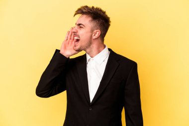 Kafkasyalı genç iş adamı sarı arka planda izole edilmiş bağırıyor ve avuç içini açık tutuyor..