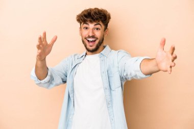 Young arab man isolated on beige background celebrating a victory or success, he is surprised and shocked.