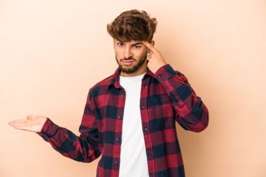 Genç Arap adam bej arka planda izole edilmiş işaret parmağıyla hayal kırıklığı jesti gösteriyor..