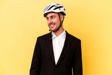 Sarı arka planda izole edilmiş bisiklet kaskı takan Kafkasyalı genç iş adamı gülümsüyor ve keyifli görünüyor..