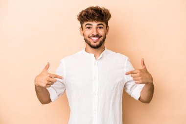 Genç Arap adam bej arka planda izole edilmiş. Parmakları aşağıda, olumlu hisler var..