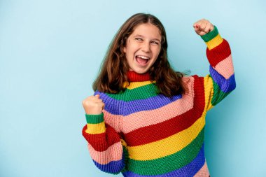 Mavi arka planda izole edilmiş küçük beyaz kız zaferden sonra yumruğunu kaldırıyor, kazanan konsept.