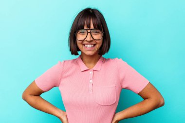 Mavi arka planda izole edilmiş genç melez kadın mutlu, güler yüzlü ve neşeli..