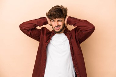 Genç Arap adam bej arka planda izole edilmiş kulakları elleriyle kapatıyor..