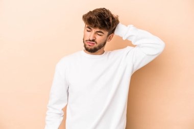 Young arab man isolated on beige background tired and very sleepy keeping hand on head.