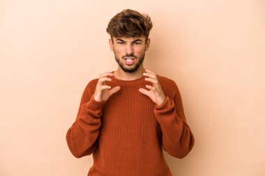 Young arab man isolated on beige background upset screaming with tense hands.