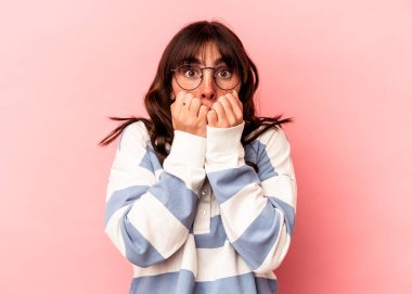 Genç Arjantinli kadın pembe arka planda soyutlanmış tırnaklarını yiyor, gergin ve çok endişeli..