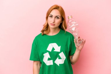 Young caucasian woman recycled plastic isolated on pink background
