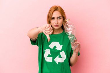 Young caucasian woman recycled plastic isolated on pink background