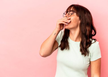 Arjantinli genç bir kadın pembe arka planda izole edilmiş gülerek, kaygısız, doğal duygularla gülüyor..