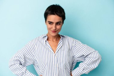 Mavi arka planda izole edilmiş genç beyaz kadın hedeflerine ve amaçlarına ulaşma hayali kuruyor.