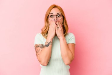 Pembe arka planda izole edilmiş beyaz bir kadın elleriyle ağzını kapatırken şok oldu..