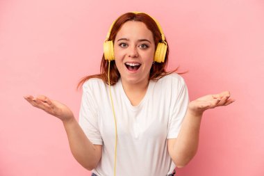 Pembe arka planda müzik dinleyen beyaz bir kadın hoş bir sürprizle karşılaşıyor, heyecanlı ve el kaldırıyor..