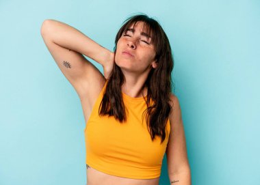 Genç Arjantinli kadın mavi arka planda yalnız başına dirsek masajı yapıyor, kötü bir hareketin ardından acı çekiyor..