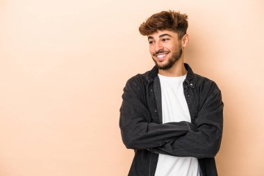Young arab man isolated on beige background smiling confident with crossed arms.