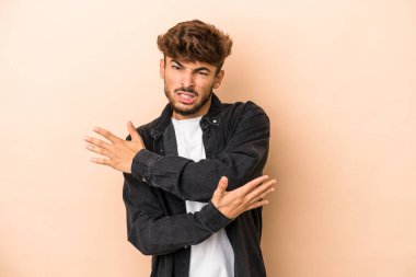 Young arab man isolated on beige background massaging elbow, suffering after a bad movement.