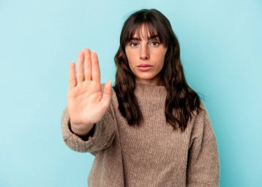 Arjantinli genç bir kadın, mavi arka planda izole edilmiş, elini uzatmış, dur işareti göstererek seni engelliyor..