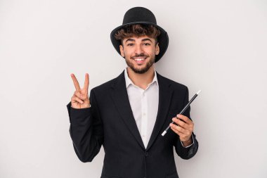Young arab wizard man holding a wand isolated on white background showing number two with fingers.