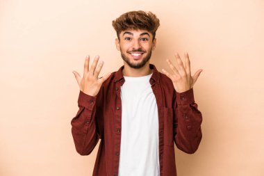 Young arab man isolated on beige background showing number ten with hands.