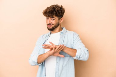 Young arab man isolated on beige background doing a denial gesture