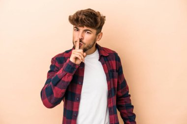 Genç Arap adam bej arka planda izole edilmiş bir şekilde bir sır saklıyor ya da sessizlik istiyor.